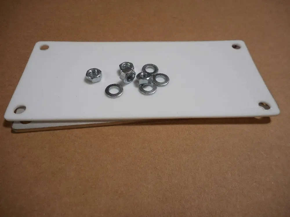 Weiße Reinigungsklappe mit Dichtungen und mehreren Metallmuttern auf einer flachen Unterlage. Teil eines Remeha-Systems.